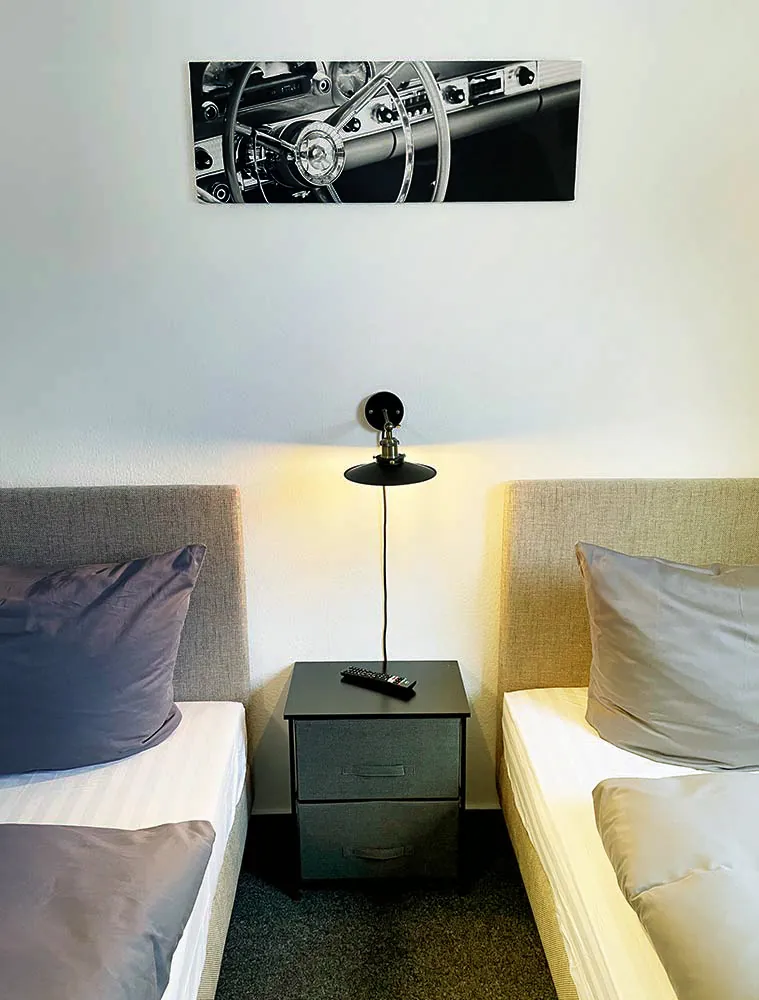 Zweibettzimmer mit Nachttisch und Wandlampe in der Pension am Fuchsbau